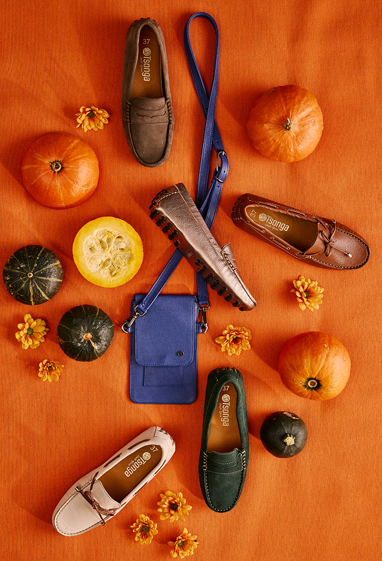 Shoes and accessories on an orange surface with pumpkins and gourds.