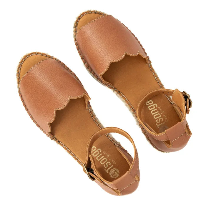 Pair of tan sandals with scalloped edges on a white background