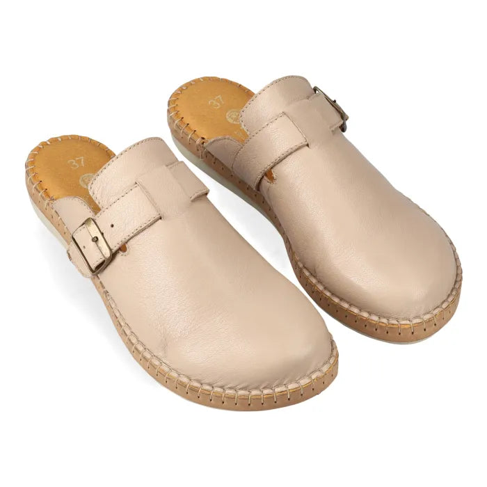 Pair of beige mules with a buckle on a white background