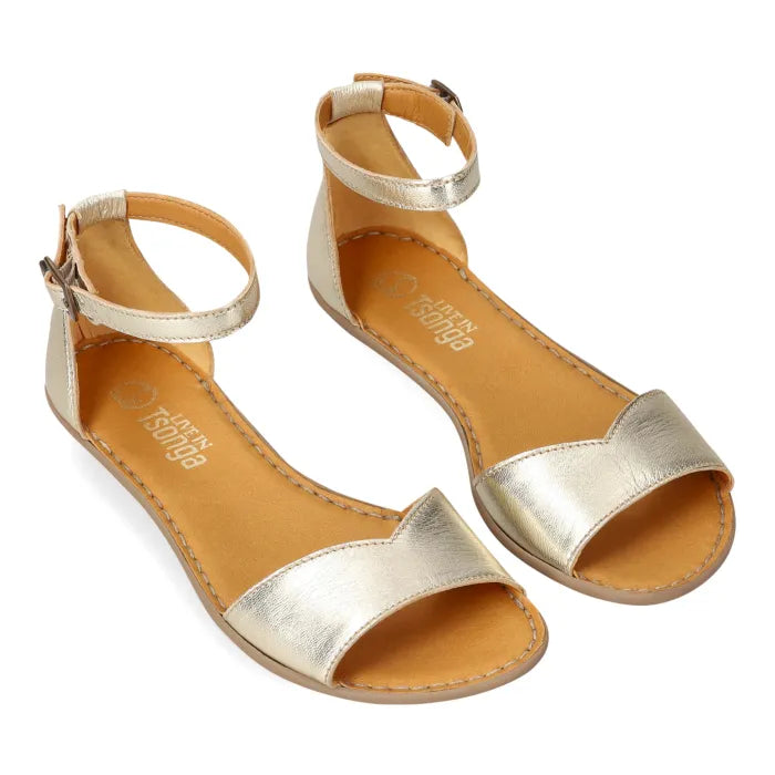 A pair of metallic gold flat sandals with adjustable ankle straps and open toes, displayed on a clean white background.