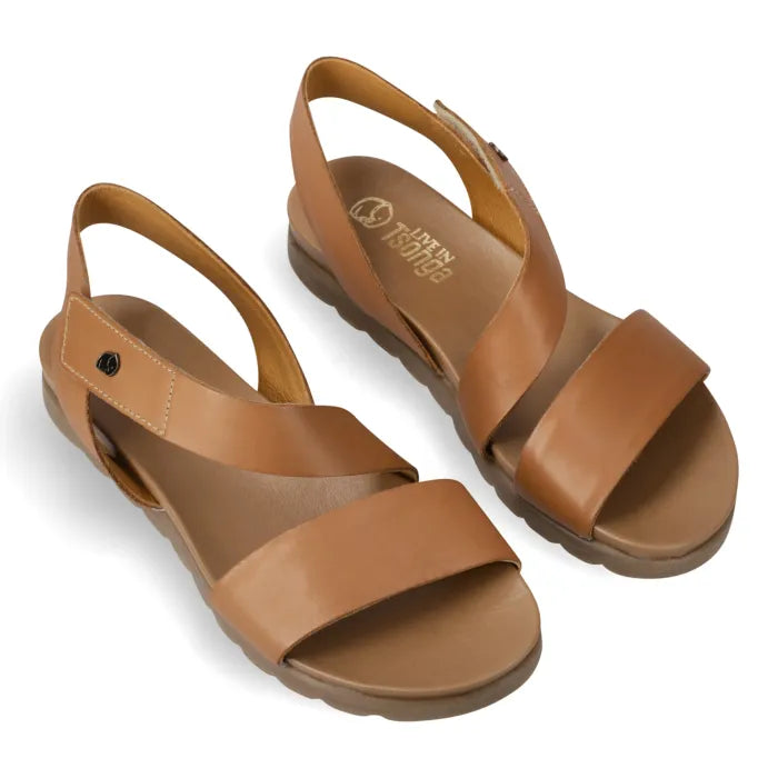 A pair of tan leather slide sandals with wide double straps and slingback ankle straps, displayed on a clean white background. The brand name 'Tsonga' is visible on the insole of the right sandal.