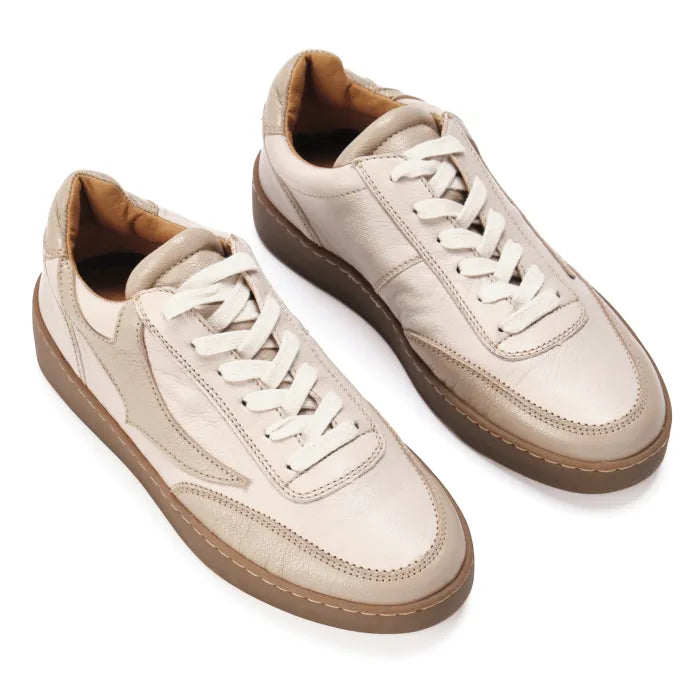 Pair of beige sneakers with white laces on a white background