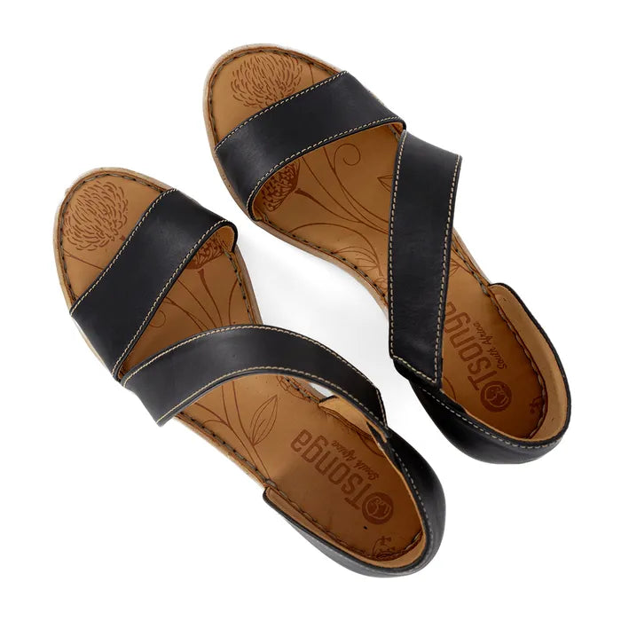 Pair of black sandals with tan soles on a white background