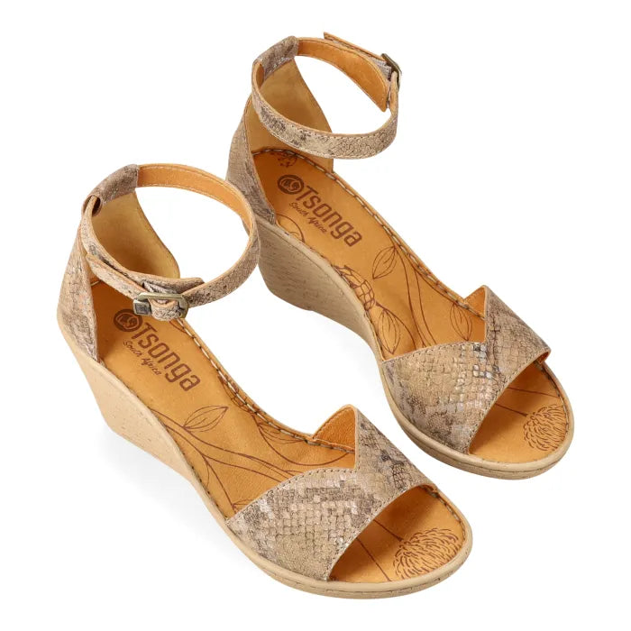 Pair of wedge sandals with snake print design on a white background