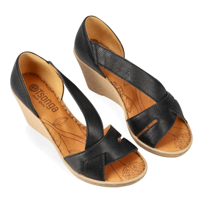 Black wedge sandals with tan soles on a white background