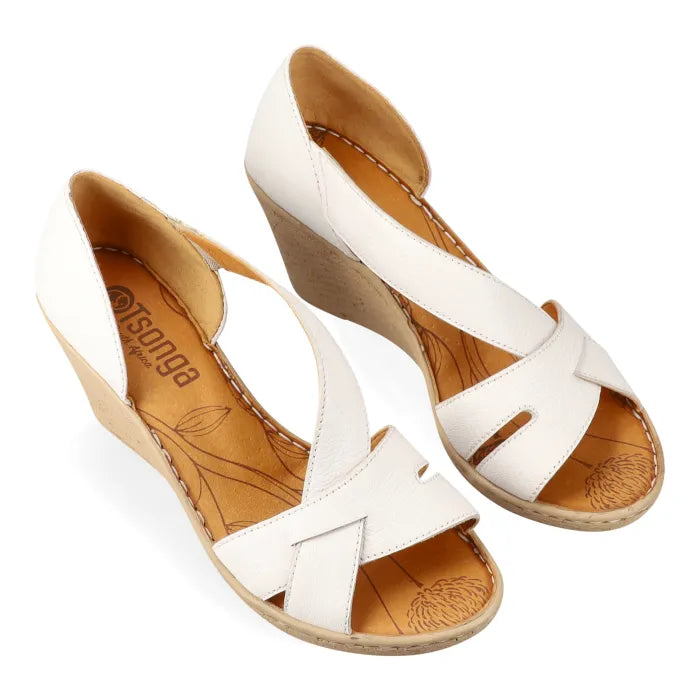 White wedge sandals with tan soles on a white background