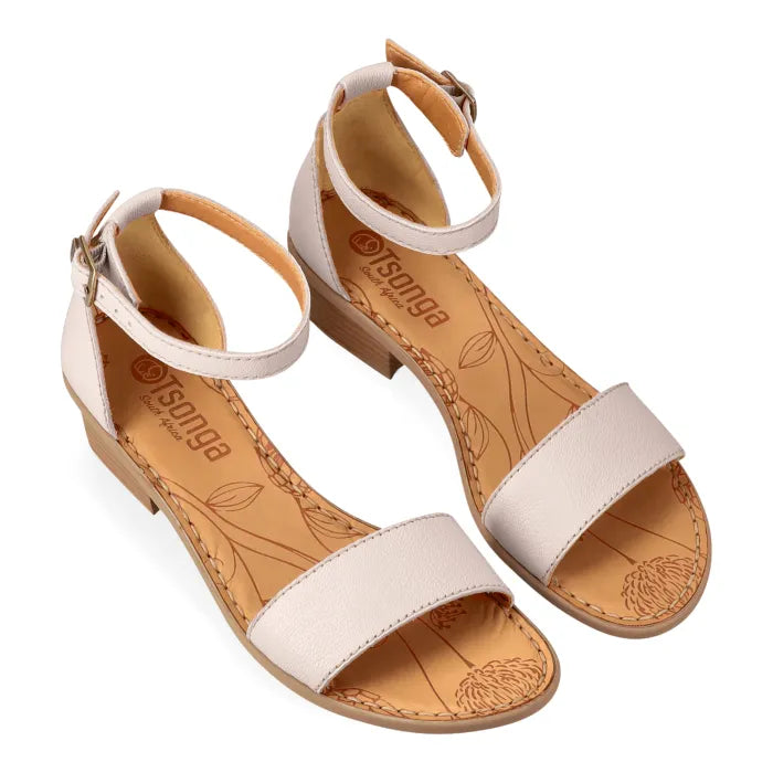 Pair of beige sandals with tan soles on a white background
