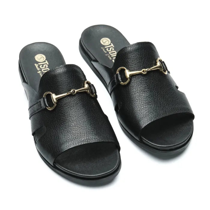 A pair of black leather slide sandals with a gold-tone horsebit detail on the strap, displayed on a clean white background.