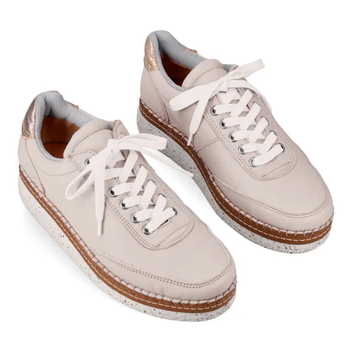 Pair of beige sneakers with white laces on a white background
