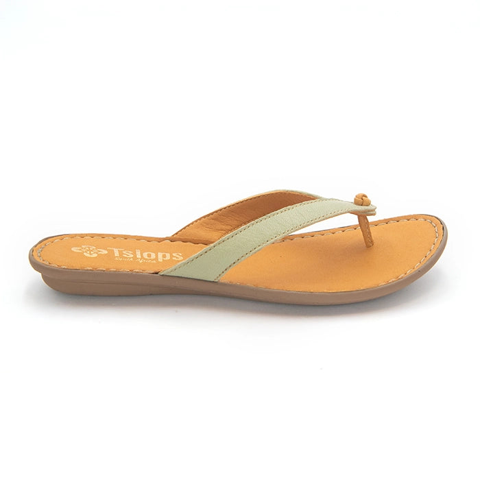 A single women's thong sandal from Tsiops, featuring a light sage green strap with a small decorative gold bead at the toe post, set on a tan footbed and a brown wedge sole, shown against a plain white background.