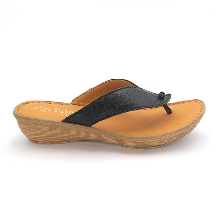 A single women's wedge thong sandal shown in side profile on a white background. The sandal features a black leather upper strap with a small black tassel detail, a tan leather footbed, and a wedge heel and sole.
