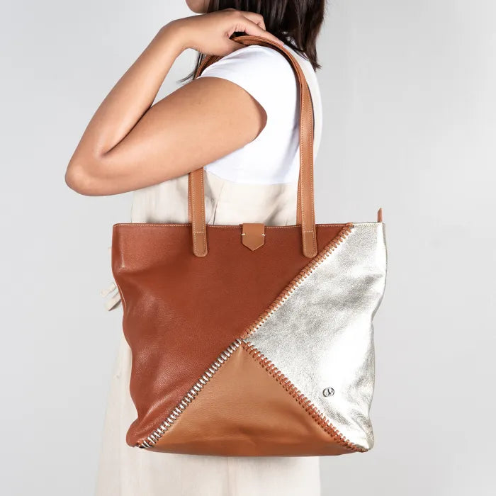 Person holding a brown and white tote bag against a plain background