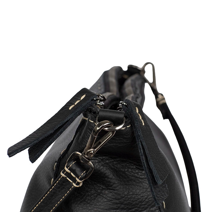 Close-up of a black leather handbag with silver trims on a white background
