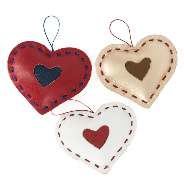 Three heart-shaped decorations in red, beige, and white with embroidered hearts on a white background.