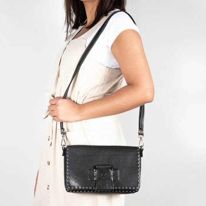Person holding a black handbag against a plain background