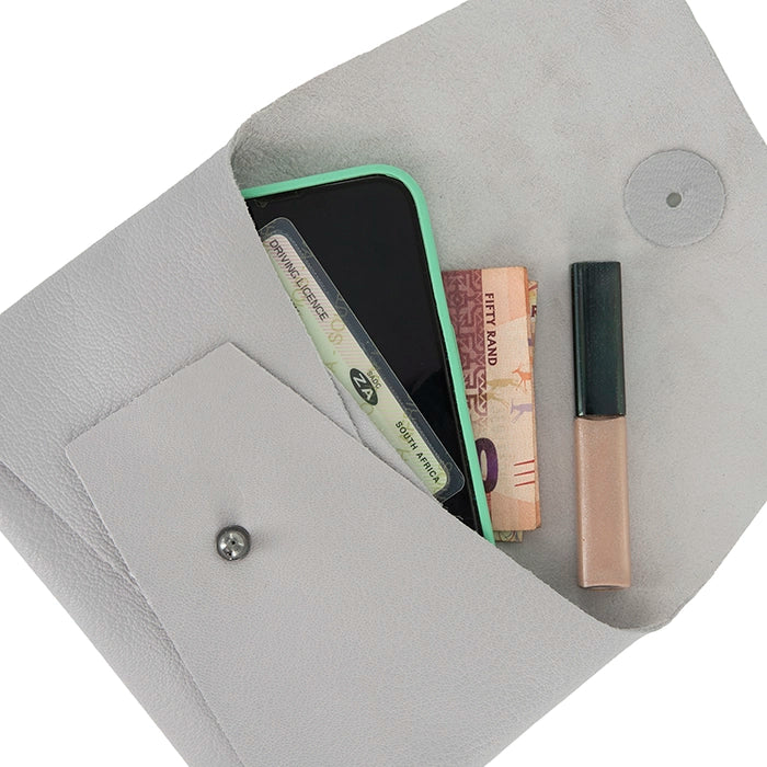 Open grey leather clutch displaying contents including a smartphone, money, ID cards, and lip gloss, with beige suede interior and front pocket.