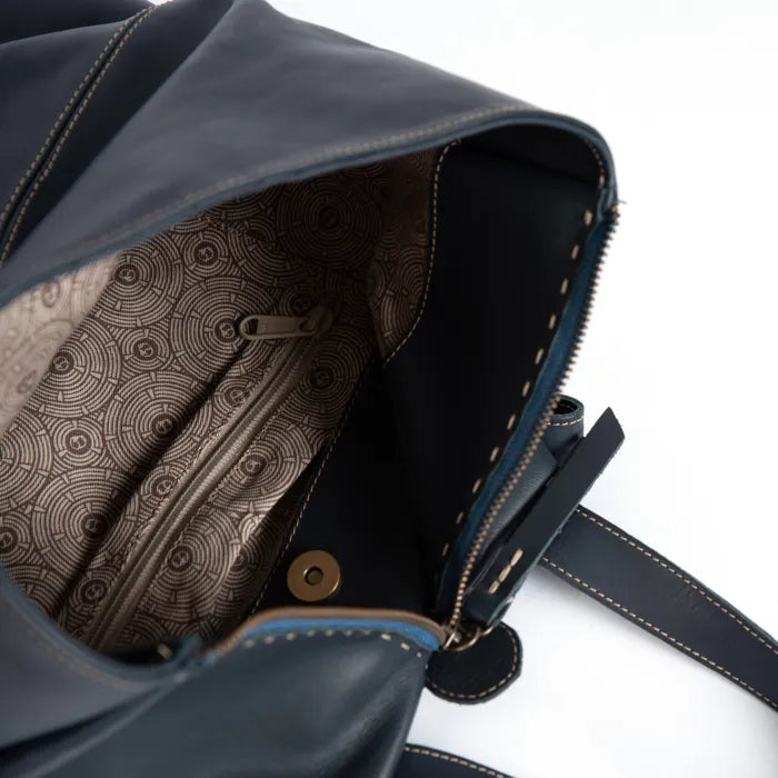 Close-up of a blue leather bag with patterned interior on a white background
