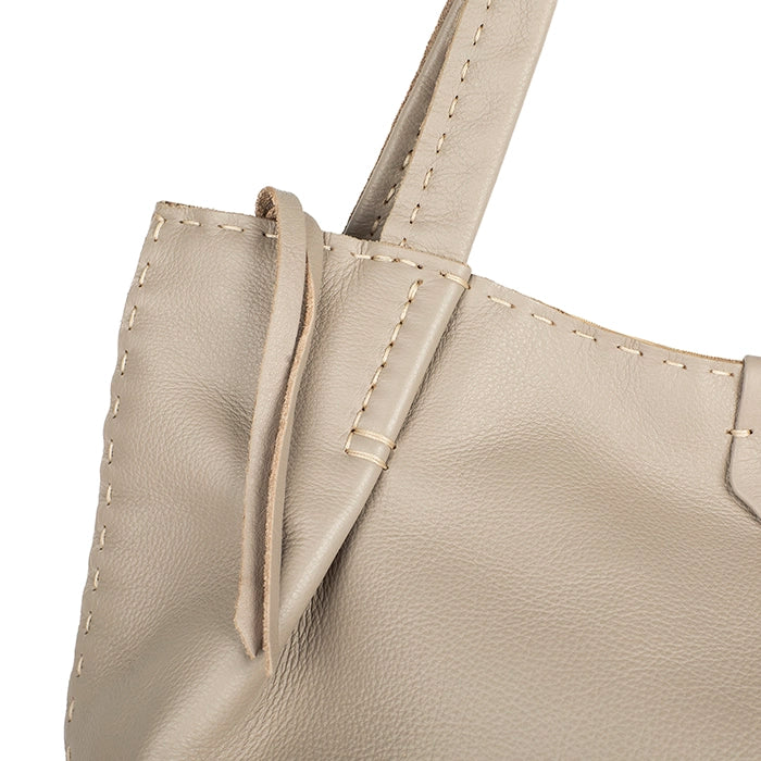 Close-up of a beige leather handbag with visible stitching on a white background