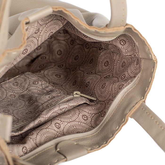 Close-up of a beige handbag with a patterned interior on a white background