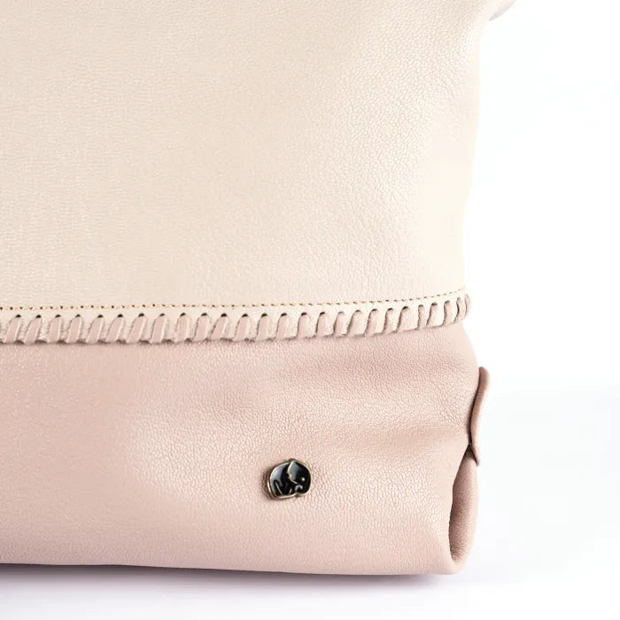 Close-up of a cream and pink leather bag with a brand logo on a white background