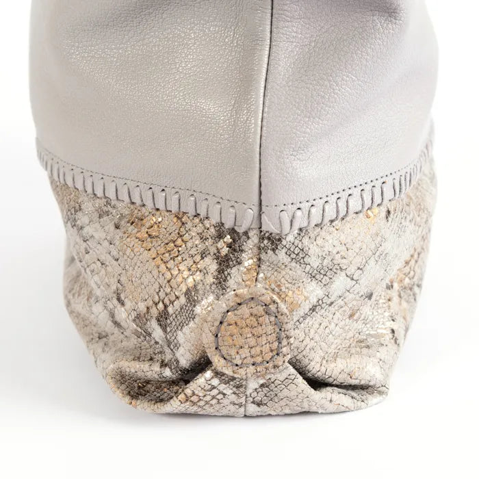 Close-up of a light grey leather handbag with snake skin pattern on a white background