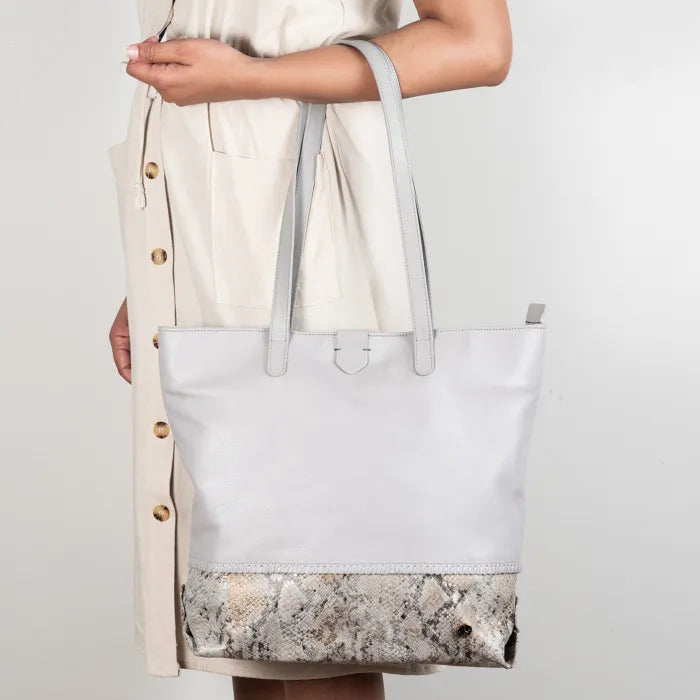 Light grey tote bag with textured bottom held by a person wearing a beige dress.