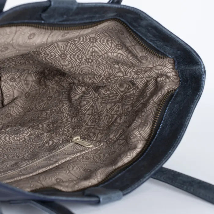 Close-up of a blue handbag with a patterned interior on a white background