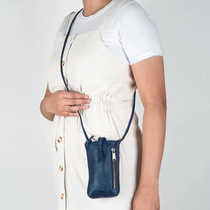 Person wearing a navy blue crossbody cellphone pouch on a plain background