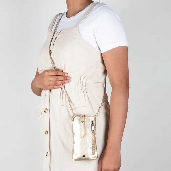 Person wearing a gold cellphone pouch on a plain background