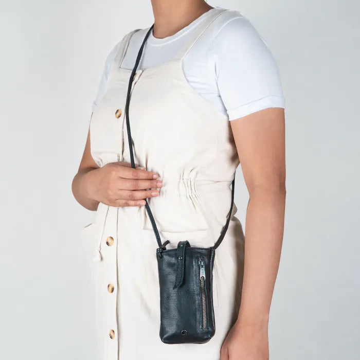 Person wearing a black leather crossbody bag against a plain background