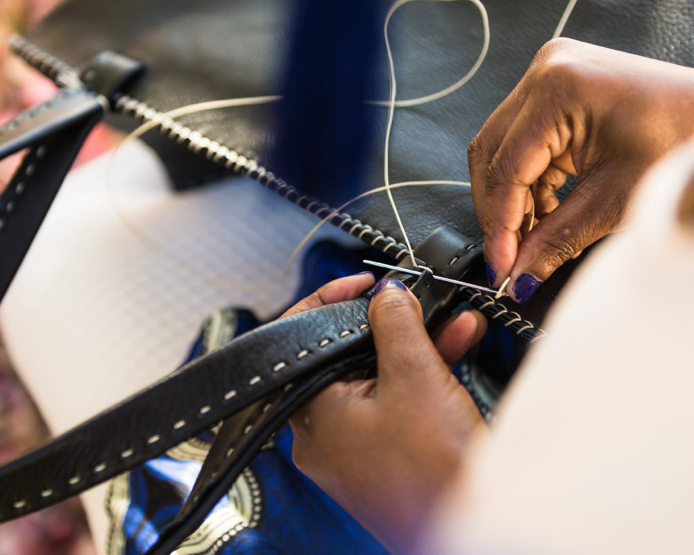 Women hand lacing a Tsonga leather handbag