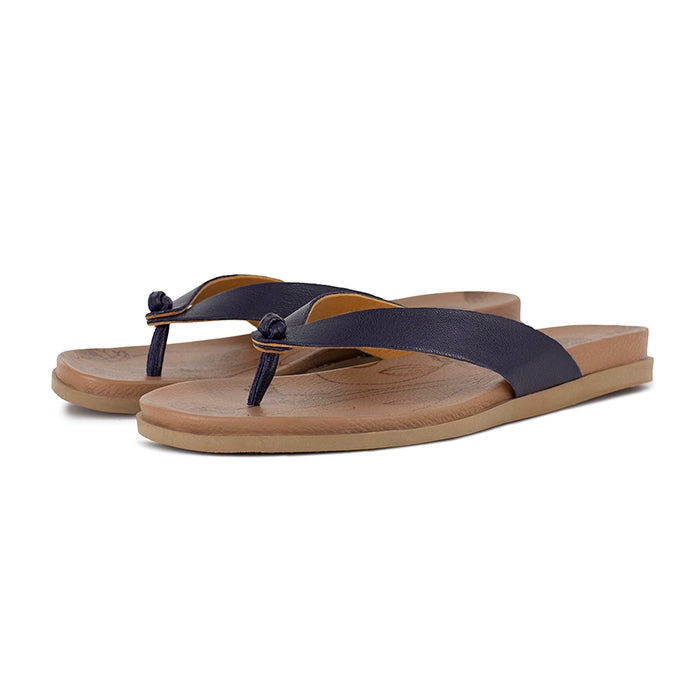 Pair of sandals with beige sole and navy straps on a white background