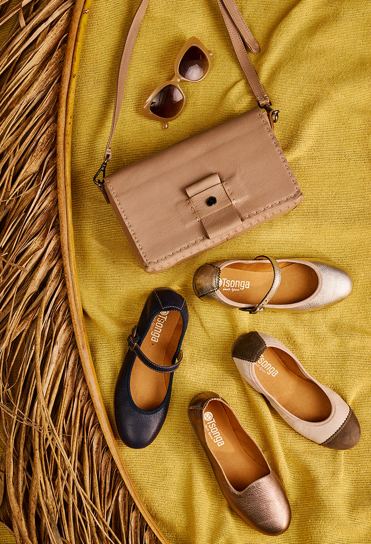 Pair of flats, sunglasses, and a small handbag on a yellow fabric background