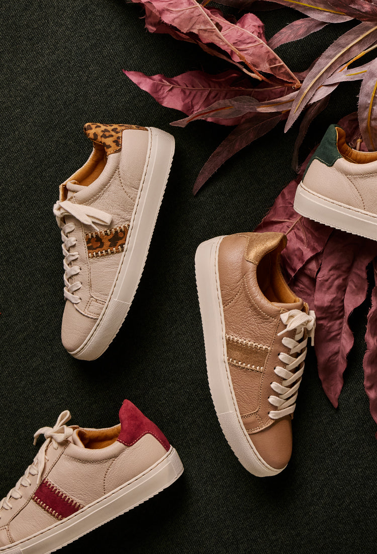 Four sneakers with unique sole designs on a dark surface with dried leaves.