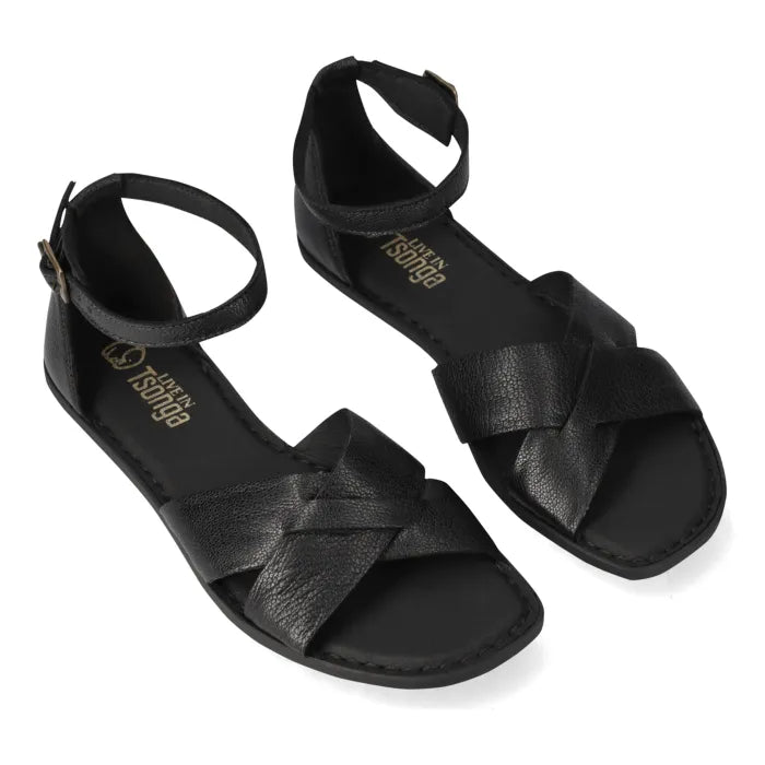 A pair of black leather flat sandals with criss-cross straps and adjustable ankle straps, shown on a white background. The brand name 'Tsonga' is printed in gold on the insole.
