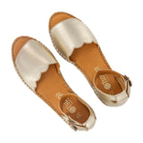 Pair of gold sandals with beige soles on a white background