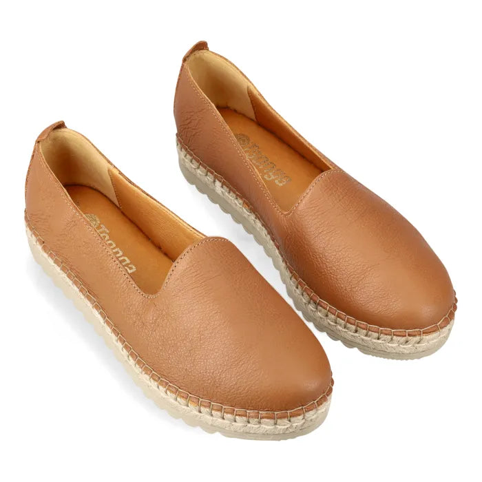Pair of tan leather espadrilles on a white background