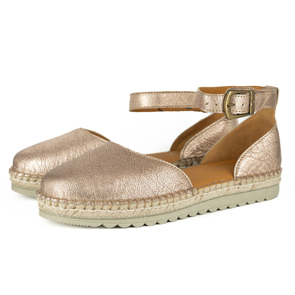 Pair of gold metallic espadrille sandals on a white background