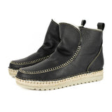 Pair of black ankle boots with beige soles on a white background