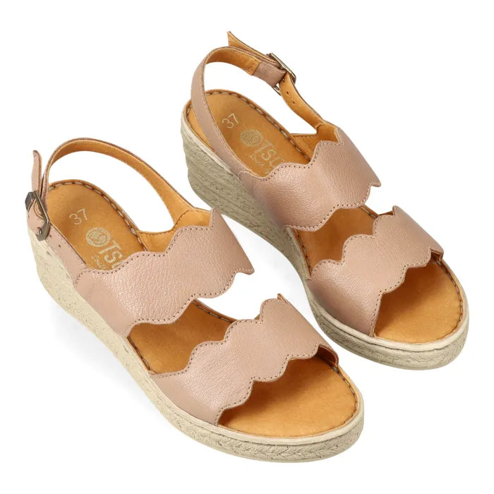 Pair of beige wedge sandals with scalloped edges on a white background