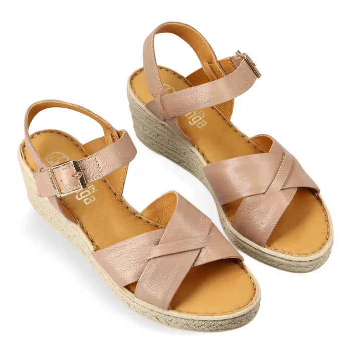 A pair of women's espadrille wedge sandals in a light beige leather, featuring criss-cross front straps, a single ankle strap with a buckle, and a natural  wedge heel, shown on a white background.