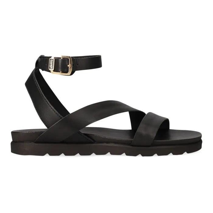 A black leather flat sandal with crisscrossing straps, a single ankle strap with a gold-tone buckle, and a chunky sole, shown in profile against a white background.
