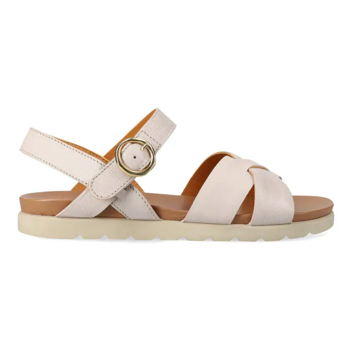 A single women's flat sandal shown in profile on a white background. The sandal features wide, crisscrossing satin straps in a light cream color, a tan footbed, a tan heel counter, and a gold-tone circular buckle on the ankle strap.