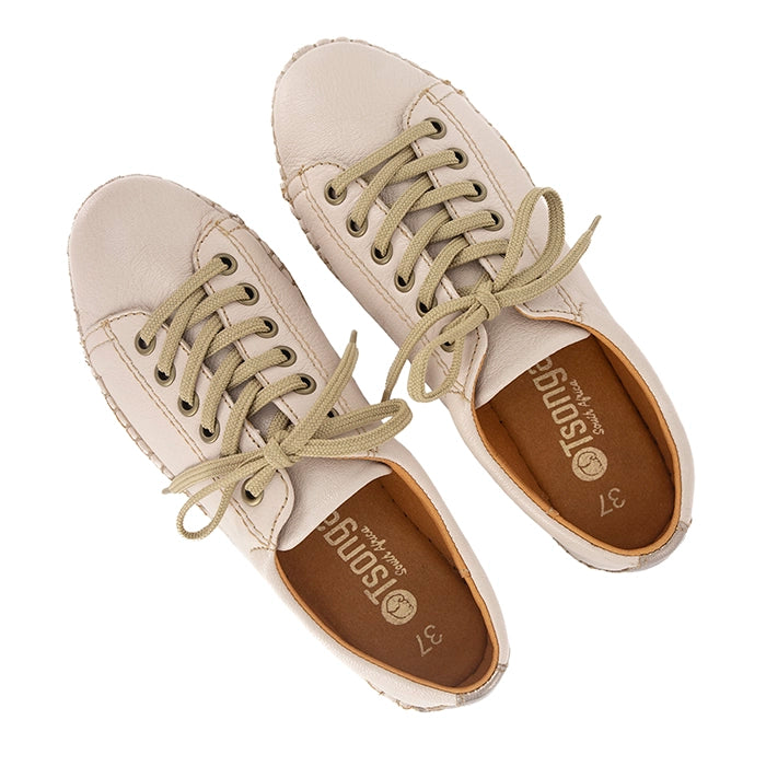 Pair of beige sneakers with green laces on a white background