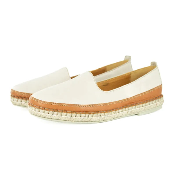 Pair of cream espadrille shoes with brown soles on a white background
