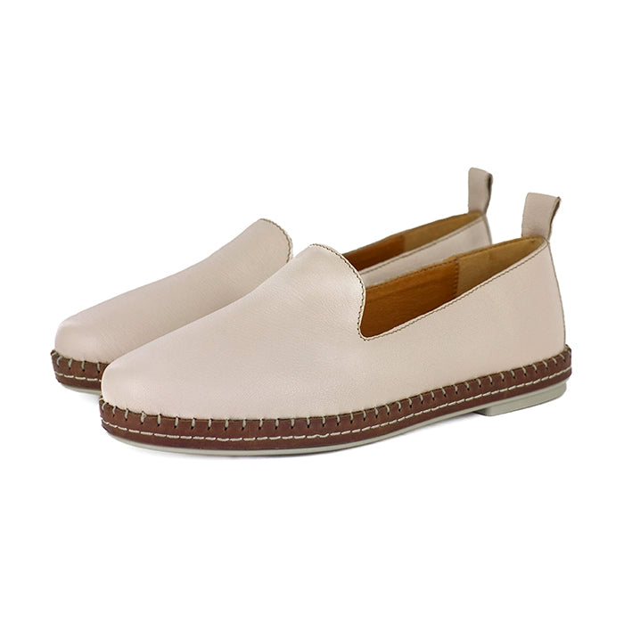 Pair of beige slip-on shoes with brown soles on a white background