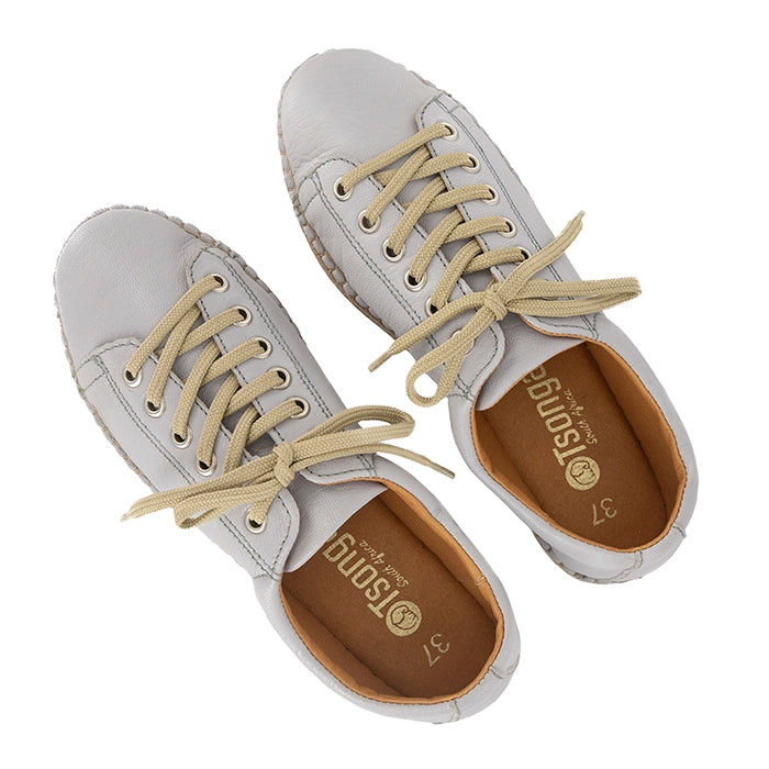 Pair of light grey sneakers with beige laces on a white background