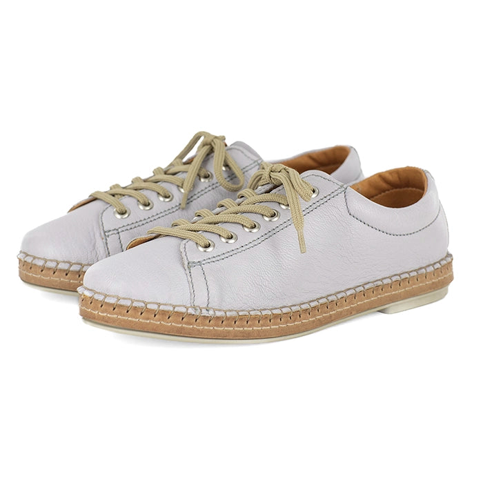 Light grey sneakers with beige soles and laces on a white background
