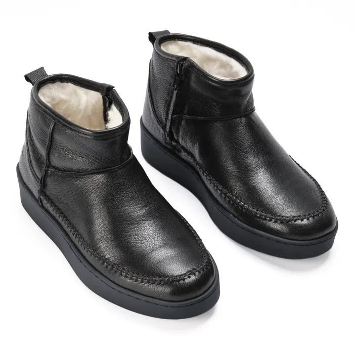 Pair of black leather boots with white wool lining on a white background