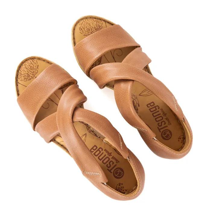 Pair of tan sandals with criss-cross straps on a white background